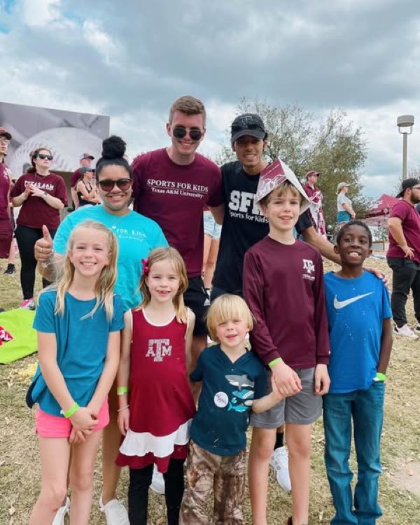 Group of college students and kids at a baseball game