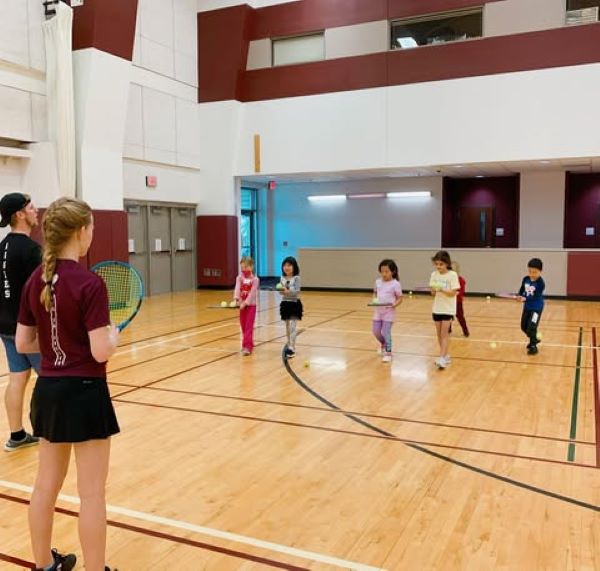 College tennis players teaching kids tennis